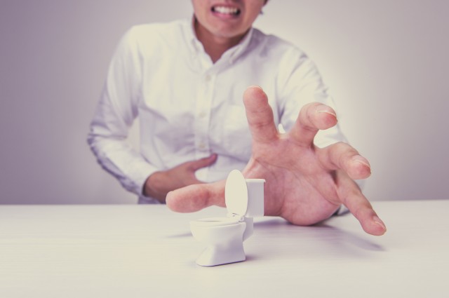 小さなトイレの模型に手を伸ばす男性